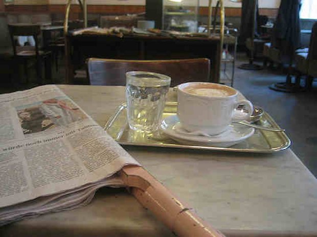 Una tazza di caffè, un giornale e un bicchiere d'acqua